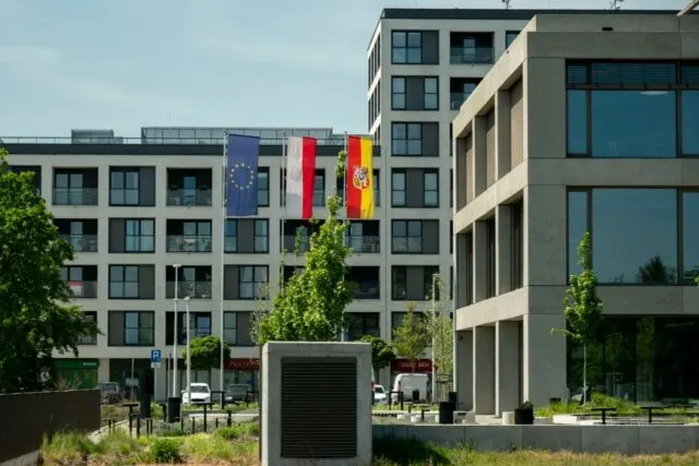 Steaguri europene fluturând în fața unei clădiri de birouri, într-o zi cu cer senin