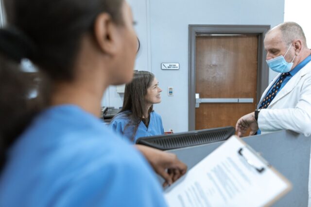 Asistentă medicală care merge pe un hol de spital slab luminat, în timpul unei ture de noapte